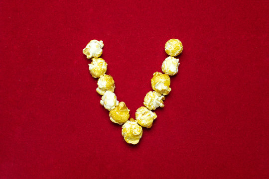 English alphabet from cinema popcorn. Letter V. Red background for design. Movie styling.
