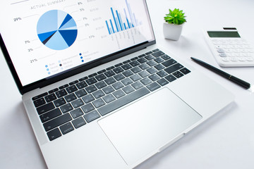 Poster - Side view of the financial business laptop on a white table with a calculator on the side. Business concept.