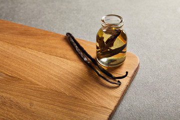 Wall Mural - Vanilla pods and bottle with essential oil on wooden surface