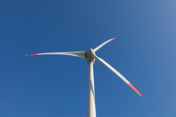 wind turbine with sun flare blue sky background view from below