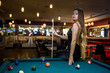 © RomanR - Beautiful woman in black dress posing with billiard cue