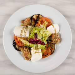 White cheese salad with tomato, eggplant and cabbage on a plate.