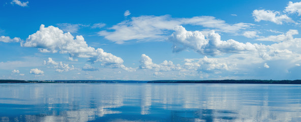 Panorama of calm lake, Kama river blue sky with clouds reflected in the water.