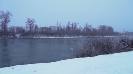 Snow falling in storm by river, Slow Motion, Pan to Left