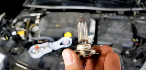 car lamp fastened with mechanic's hand in a workshop to put on a vehicle.