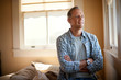 © Erickson Stock - Middle-aged man smiles as he looks out of the window of his bedroom.