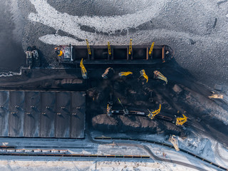 Loading coal mining in port on cargo tanker ship with crane bucket of train. Aerial top view