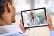 © JPC-PROD - virtual live chat with the patient with digital tablet and a doctor via internet. In-home care for a young male patient in telemedicine or telehealth,