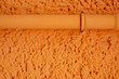Orange verputzte Hauswand mit Rohrleitung