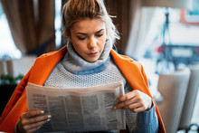 Young Businesswoman Reading Daily Newspaper In A Cafe.