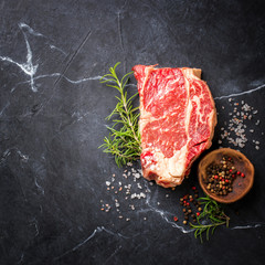 Wall Mural - Raw Fresh Marbled Meat Beef Steak. Herbs and Seasonings on a black marble   Background Rosemary Pepper and Salt Ingredients for Cooking Top View Copy space for Text