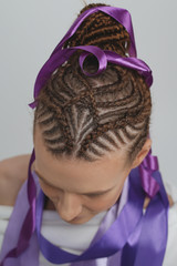 Wall Mural - girl on a white background, hair braided in a tight hairstyle in the African style on European hair, close-up of the head, gray ribbons, design, decor hairstyles