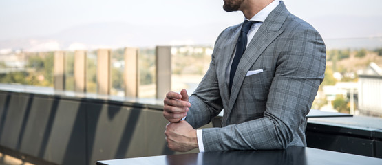 Wall Mural - Man in expensive custom tailored suit standing and posing outdoors on balcony