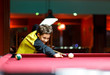 © Natali - Cute boy in yellow t shirt plays billiard or pool in club. Young Kid learns to play snooker. Boy with billiard cue strikes the ball on table. Active Leisure, sport, hobby concept