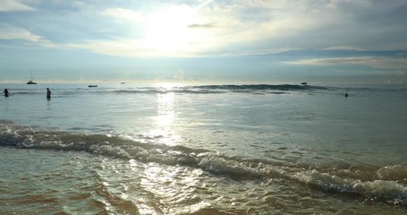 Wall Mural - Indyllic beach with brigh sunlight and calm water waves rolling on sand shore