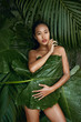 Beauty. Woman covering naked body with leaf at tropical nature