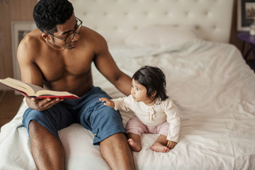 Wall Mural - beautiful little girl listening to dad reading fairy tale while resting in the bedroom. close up photo, copy space, interest, lifestyle