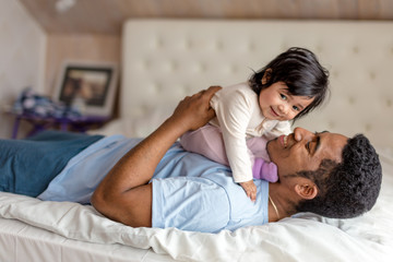 Wall Mural - cheerful caring daddy enjoying time with a baby girl,close up side view photo