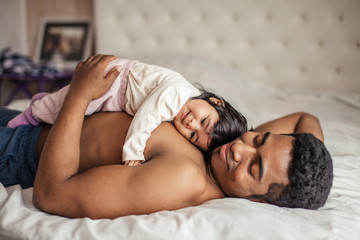 Wall Mural - man getting pleasure from lying with favourite daughter, close up side view photo