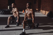 Focused male african and caucasian athletes showing determination and endurance exercising legs and back musculs during body core crossfit workout