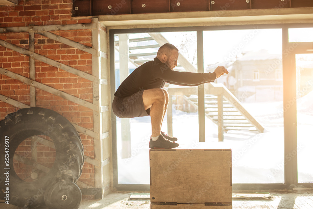 Caucasian determined sportsman performing plyometric box jumps indoor ...