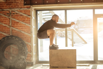 Wall Mural - Caucasian determined sportsman performing plyometric box jumps indoor, in crossfit functional workout