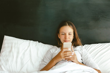 Canvas Print - 12-14 years teenag girl using smartphone in bed