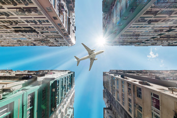 Wall Mural - Airplane flying over business skyscrapers