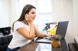 © F8  \ Suport Ukraine - Smiling young woman in the kitchen looking at her laptop