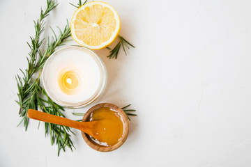 Natural skincare still life with candle, manuka honey, lemon and rosemary herbs  top view with copy space, natural spa still life on white background