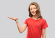 © Syda Productions - people concept - smiling teenage girl with long hair in red t-shirt holding something imaginary on empty hand over grey background