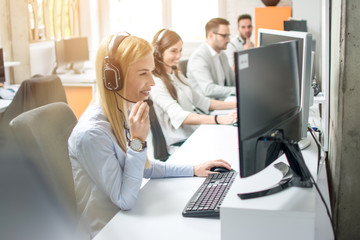 Group of customer service operators working in row in call center office