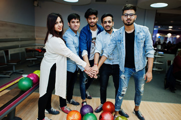 Group of five south asian peoples having rest and fun at bowling club. Putting their hands together, friends showing unity and teamwork.