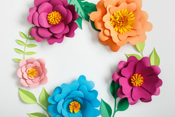 Wall Mural - top view of multicolored paper flowers and green leaves on grey background