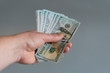 © jollier_ - Hand with dollars on a gray background. dollars money finance currency in hand on gray background. vertical photo