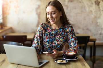 Wall Mural - Young woman with laptop in cafe