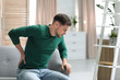 © New Africa - Young man suffering from back pain at home