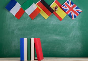 Fototapete - flags of Spain, France, Great Britain and other countries and books on the background of the blackboard