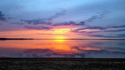 Background with abstract ultra purple pink sunset sun and cloudy sky reflecting in Razna lake water, Latvia