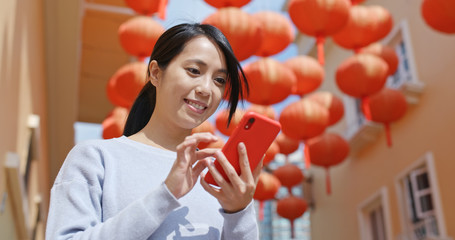 Wall Mural - Woman use of cellphone for sending red packet with mobile app over red lantern background