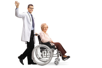 Poster - Young smiling positive male doctor waving and pushing a disabled senior woman in a wheelchair