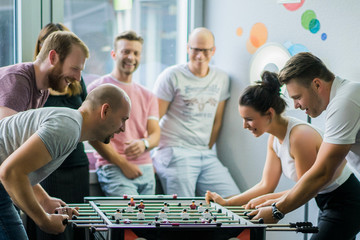 happy managers playing table football at office and having fun together