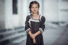 Beautiful Little Girl In An Old Dress On The Background Of The Architecture Of The Historic Center