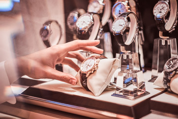 Close-up of the seller's hand shows the exclusive men's watch from the new collection in the luxury jewelry store