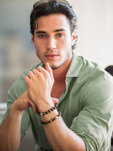 Attractive Young Man Indoors Wearing A Shirt And Beaded Bracelets