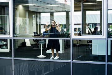 young woman standing in an office with a large window