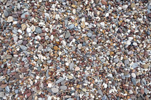Background From Many Small Smooth Pebble Stones On The Sea Beach On Sunny Day Top View Close-up
