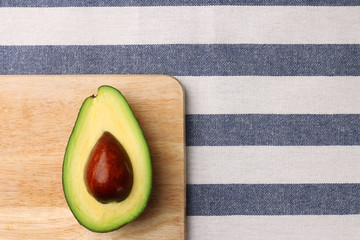 Wall Mural - half avocado on wooden and textile background top view