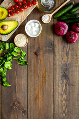 Wall Mural - Fresh organic vegetables on dark wooden background top view space for text. Kitchen desk for preparing salad