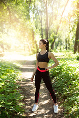 Athletic girl running in the nature. Female jogging on bridge at the park. Young woman stretching before run. Fitness model working out outdoor. Concept of healthy lifestyle.